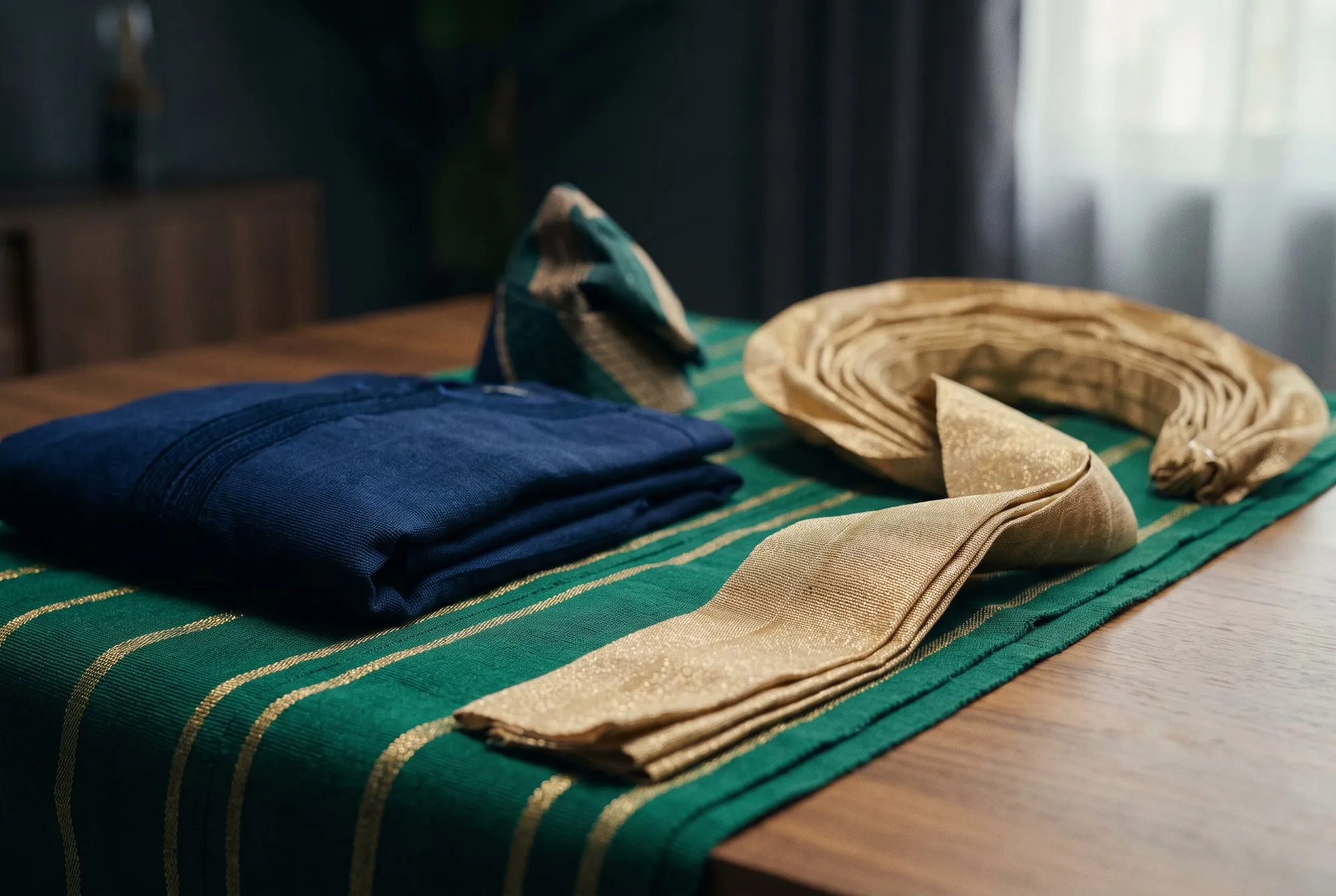 Handwoven Nigerian cloth in green and gold, folded with a matching headtie